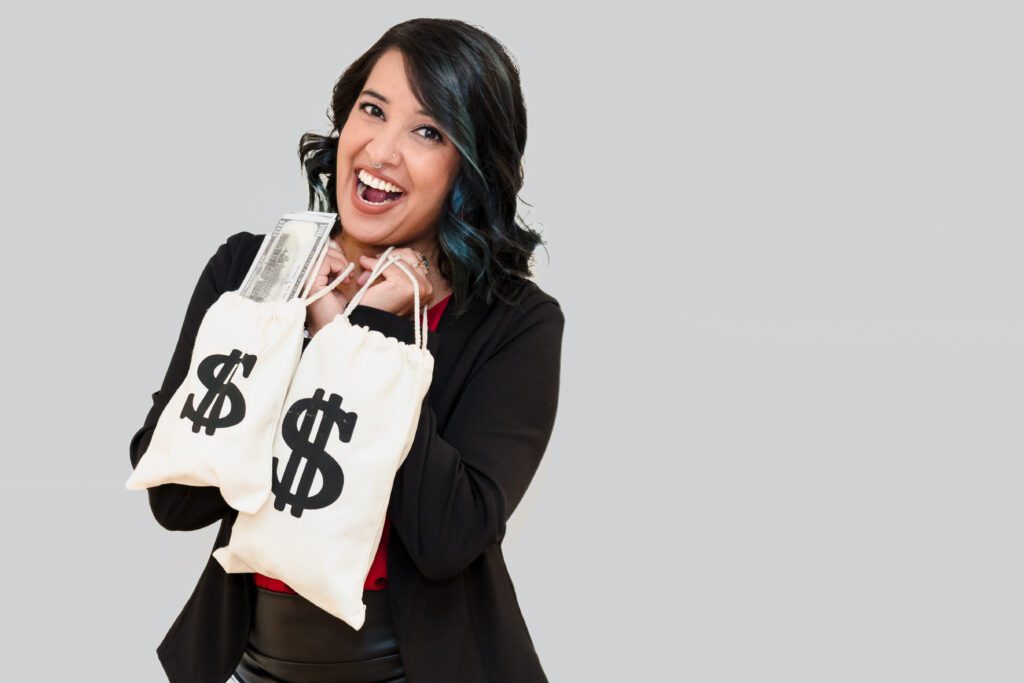 brand headshot of a business coach holding two bags with a money sign, laughing.