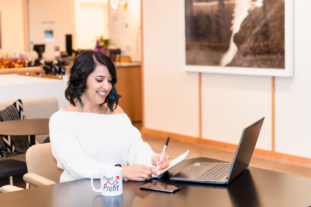 brand photo of a business coach taking notes in a notebook, laptop opened