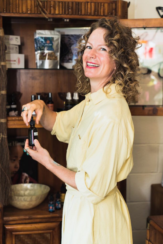 woman opening an oil essence, looking over the shoulder, and smiling 