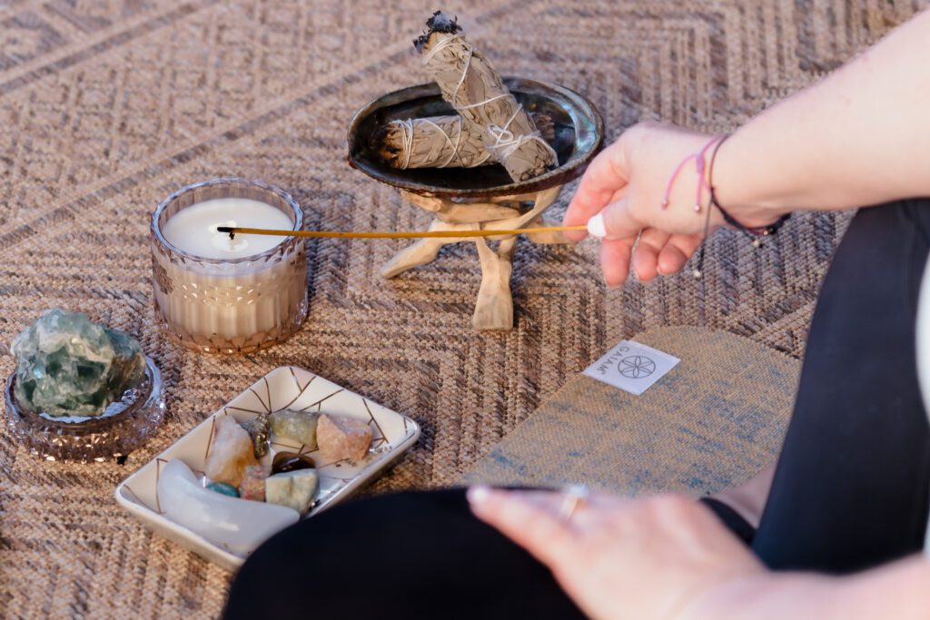 brand photo of coach lighting up a candle, among crystals and sage