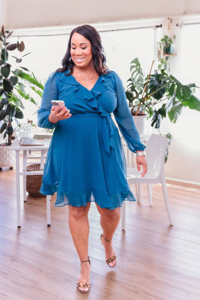 woman wearing a blue dress walking and checking her phone