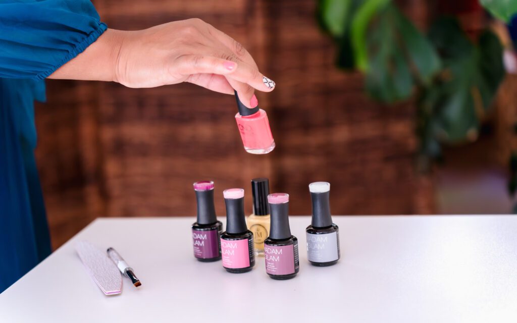 detail photo of a business owner putting nail polish at a table among a collection of nail polish