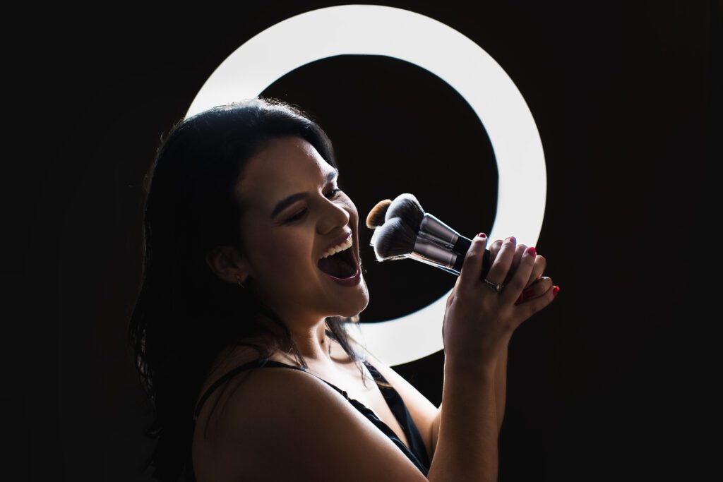 makeup up artist plays with brushes, and the ring light shines in her background