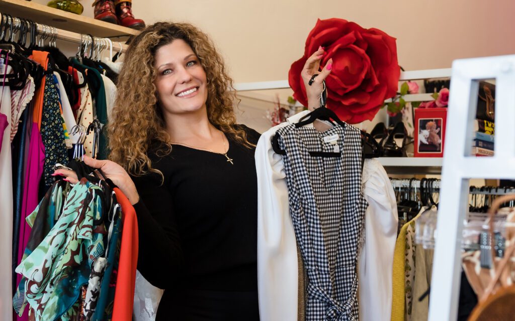 brand photo of a boutique owner holding hangers full of clothing. 