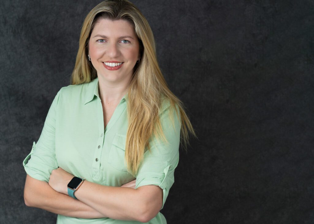  headshot of a blonde woman in a stance pose, arms crossed