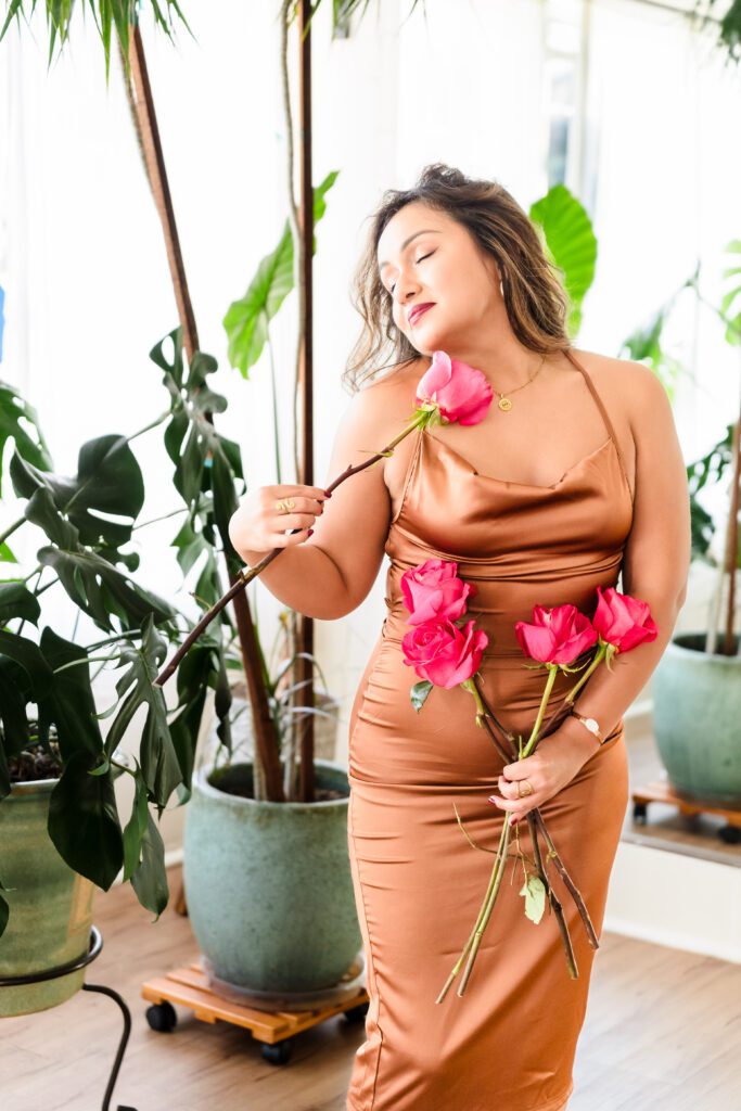 woman wearing a silk luxury dress and holding roses in a sensual pose