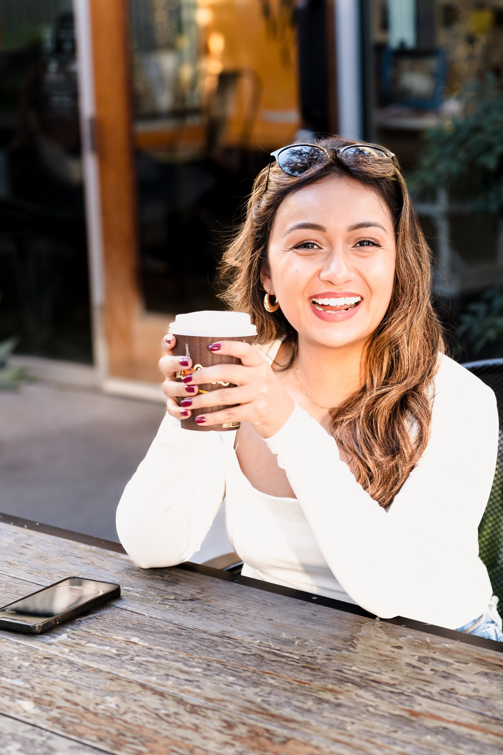 brand photo of a coach holding a cup of coffee and smiling