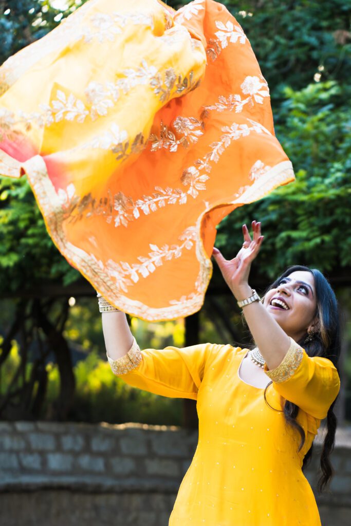 brand photo of a woman wearing an Indian outfit and throwing a sari to the air