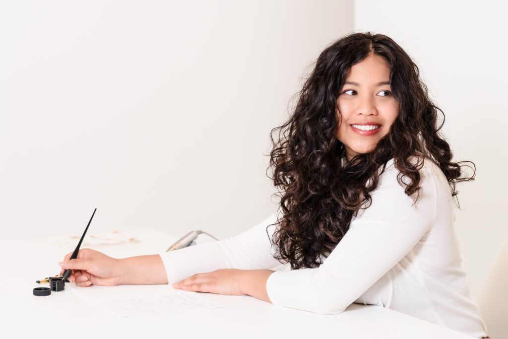 brand photo of a Calligrapher working in her desk, looking over the shoulder