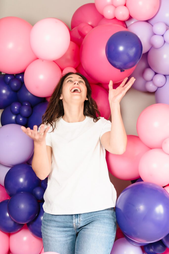 brand photo of a balloon decoration business owner playing with balloons in the air