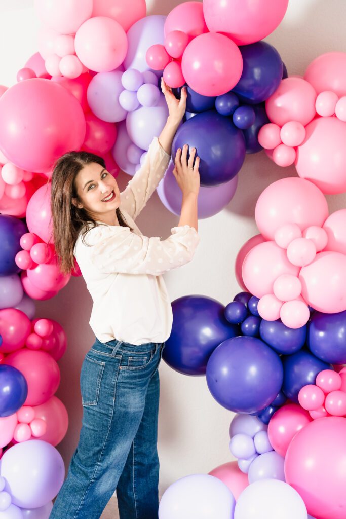 brand photo of a balloon business owner holding the balloon decoration she crafted.