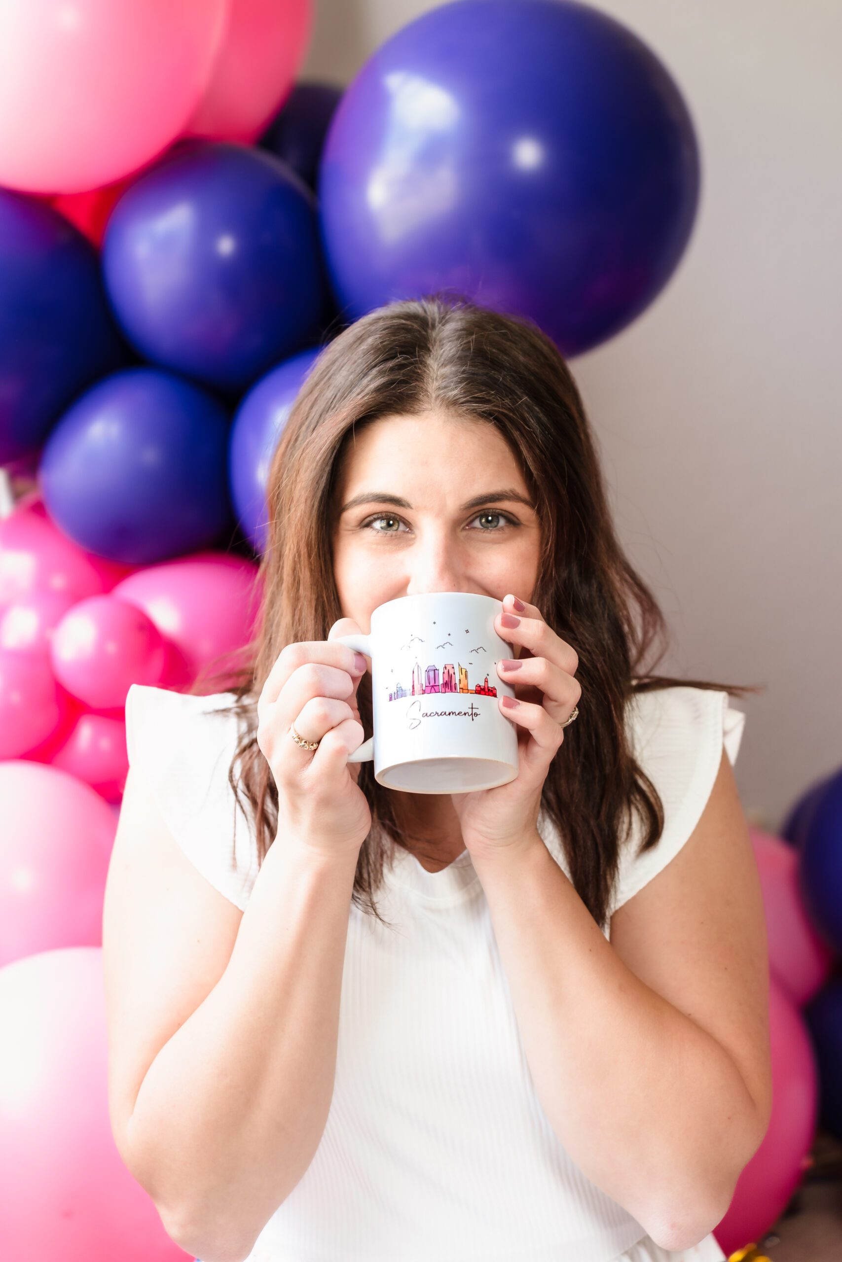 brand photo of a balloon business owner holding a on-brand mug