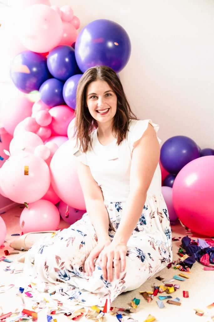 woman posing sit among balloons and confetti