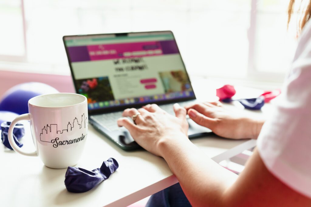 detail shot of hands in the laptop and a coffee mug showcasing the skyline of Sacramento.