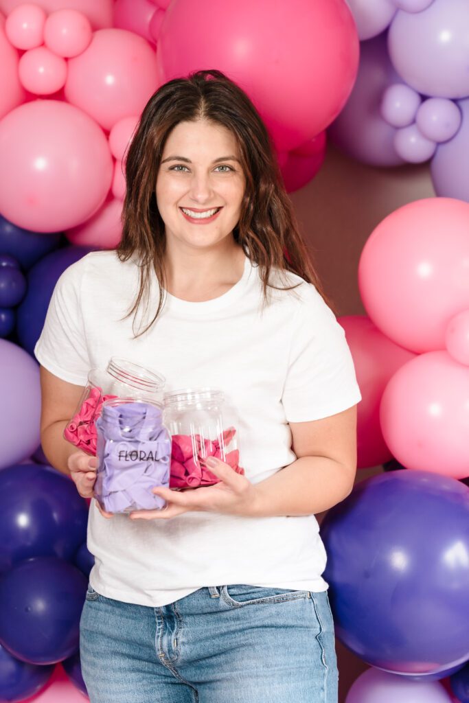 brand photo of a balloon business owner holding containers full of balloons