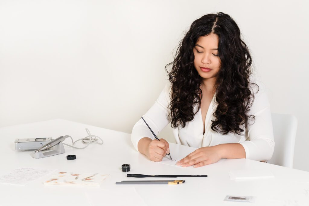 calligrapher doing her craft in a desk full of pen and ink