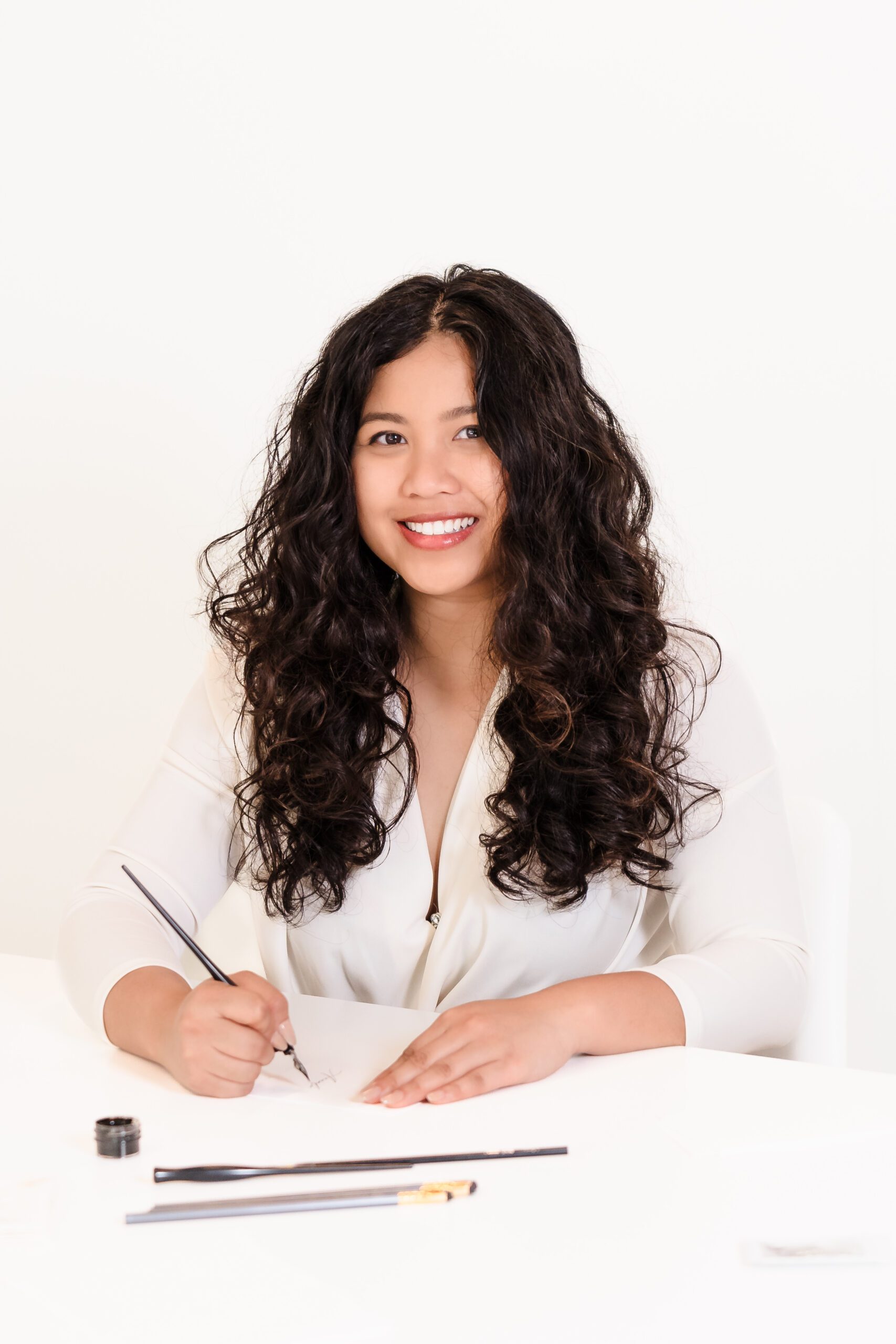 Calligrapher's Headshot posing with a pen on the desk