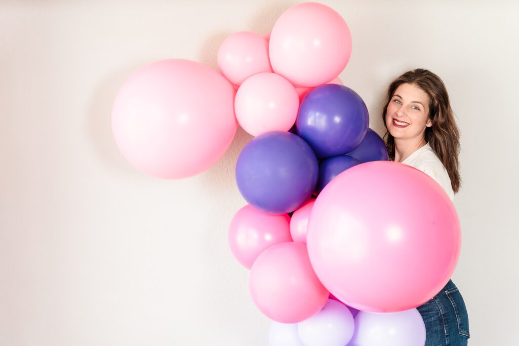 brand photo of a business owner holding a lot of balloons