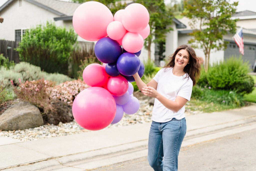 woman holding balloons walking in the middle of the street
