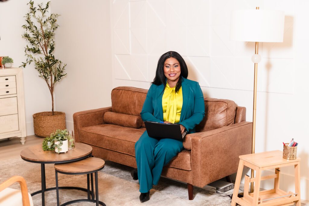 woman wearing a yellow and green outfit, posing sit with laptop in her lap