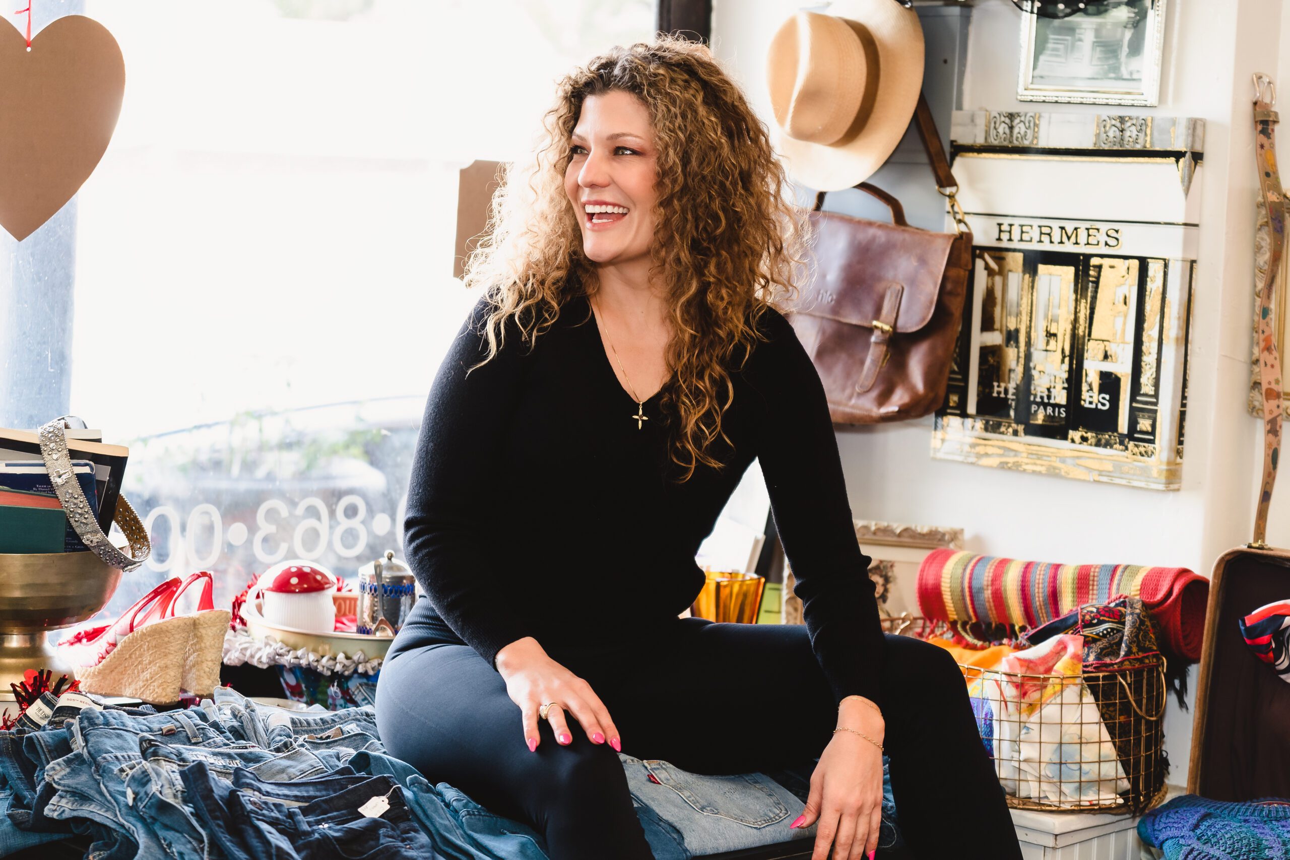 Boutique owner seated close to the window, smiling.