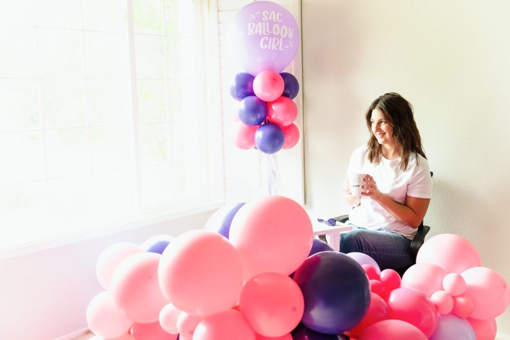 woman seated close to the window surrounded by balloons 