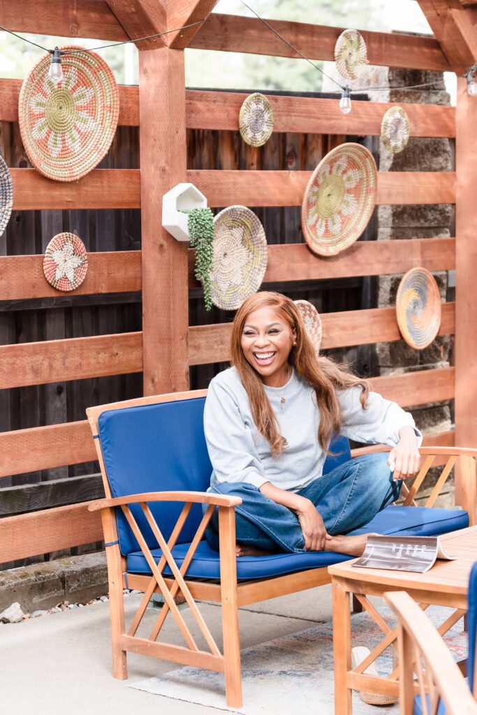 candid image of a woman smiling, seated on a boho patio