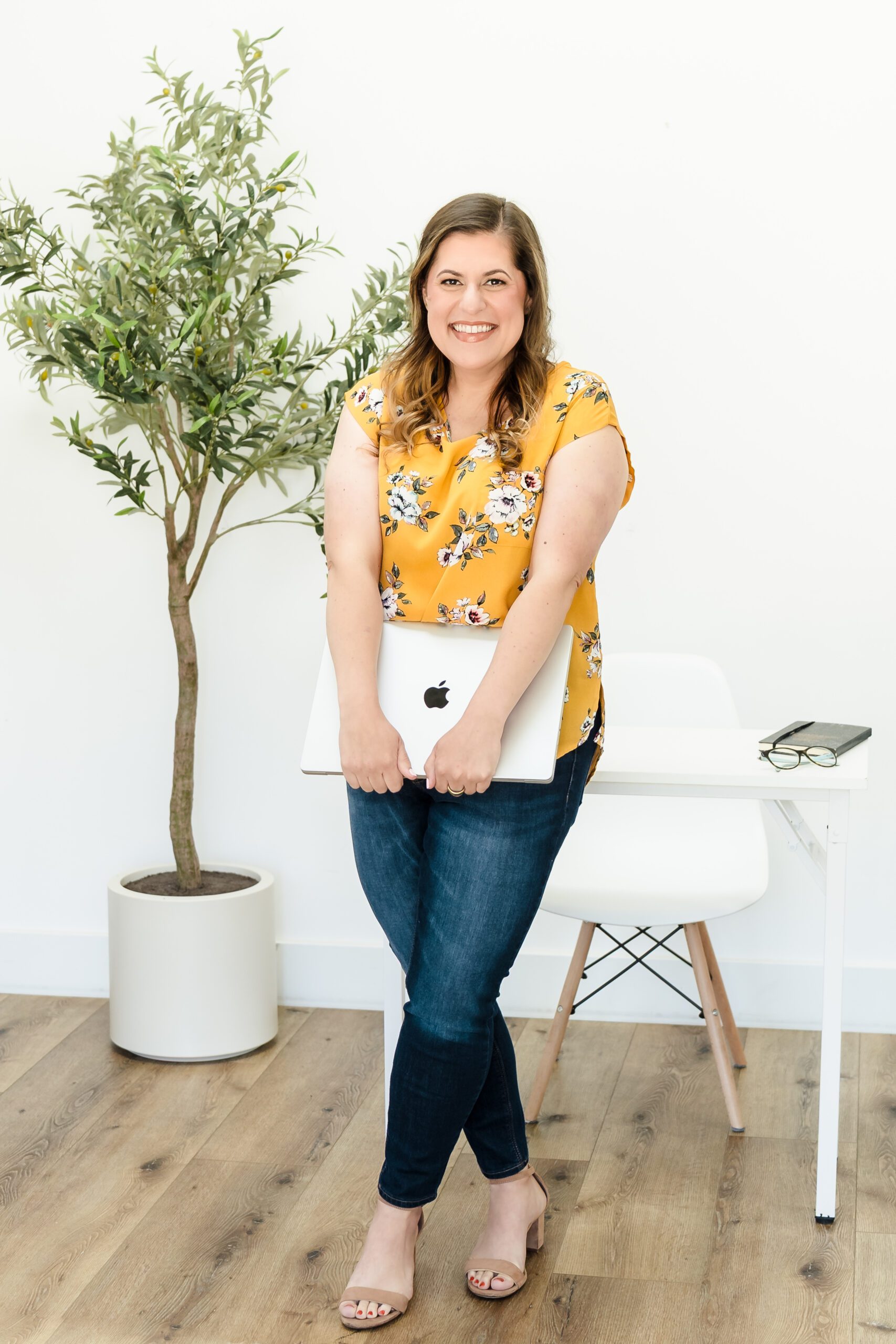 brand photo of a web designer holding a laptop and leaning on an office desk