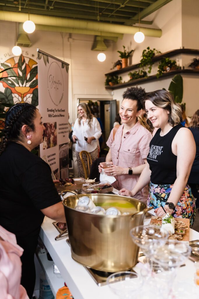 Women engaging with a local vendor at the Powered by Women networking celebration in Sacramento, photographed by Geise Pinto Photography.